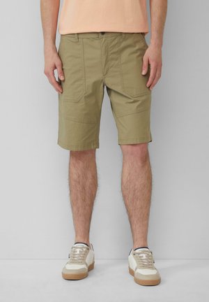 Helle khakifarbene Shorts mit mehreren Taschen, geradem Schnitt und glatter Textur. Dazu werden beige und weiße Sneaker mit Schnürdesign getragen.