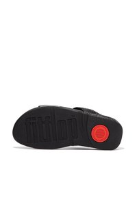 Talpa neagră cu textură din cauciuc prezintă marca "fitflop" gravată. Un accent circular roșu este vizibil. Forma este ergonomic, cu o margine ușor ridicată.