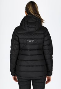 Czarna puchowa kurtka z kapturem, z pikowanymi sekcjami i logo na górnej części pleców. Gładka struktura i pewne dopasowanie na dole.