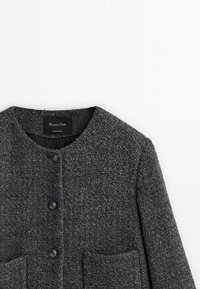 Manteau gris texturé avec un col rond, deux poches avant et une fermeture à cinq boutons. Étiquette visible à l'intérieur du col.