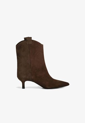 Stivale alla caviglia in suede marrone con punta affusolata, tacco a stiletto sottile e dettaglio a linguetta sul retro. Texture liscia e design minimalista.