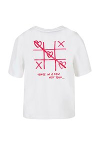 T-shirt bianco in cotone con un design di tris in rosso, con cuori e la scritta "TRE IN FILA NON IL TUO..." stampata sul retro.