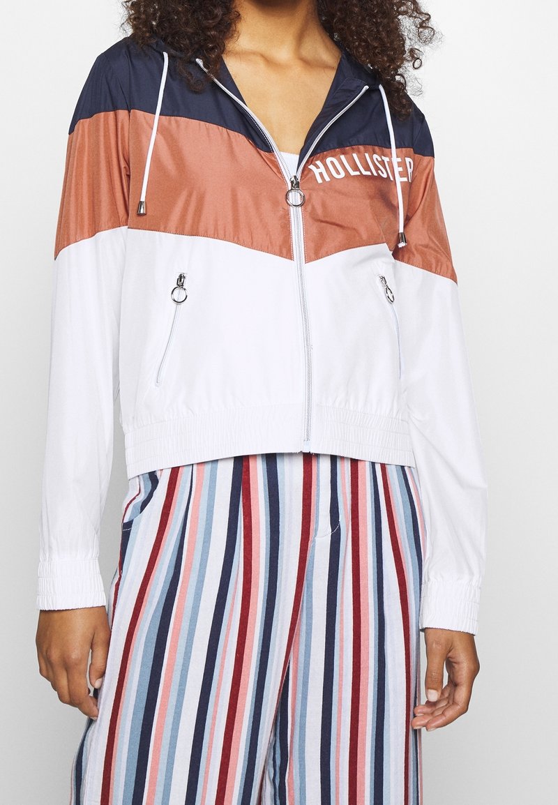 Färgad vindtäta jacka i marinblått, rostfärgat och vitt med dragkedja fram, elastiska manschetter och två sidofickor. Funktioner "HOLLISTER"-logotyp i vitt.