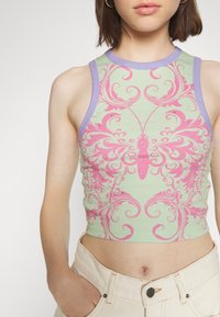 Ljusgrön crop top med lila halsringning, med en dekorativ design i rosa och små rhinestones. Material av bomull med en åtsittande passform.