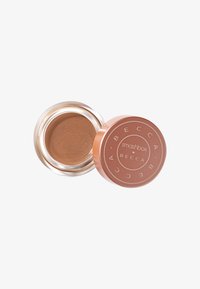 Bruine crèmeproducten in een ronde, roségouden spiegelcontainer met een gelabelde deksel. Soepele textuur, weerkaatsend licht.