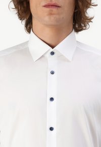 Weißes Langarmhemd mit strukturiertem Kragen, blauen Knöpfen, glatter Textur und sauberer Naht, geeignet für formelle Anlässe.