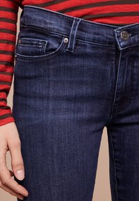 Mörkblå denimjeans med slim fit, med en knäppbar midja, framfickor och subtil vertikal textur.