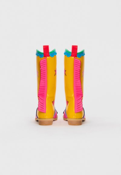 Yellow cowboy boots with pink accents, scalloped green trim, and pink star patterns. Features a textured pink side design and a small heel.
