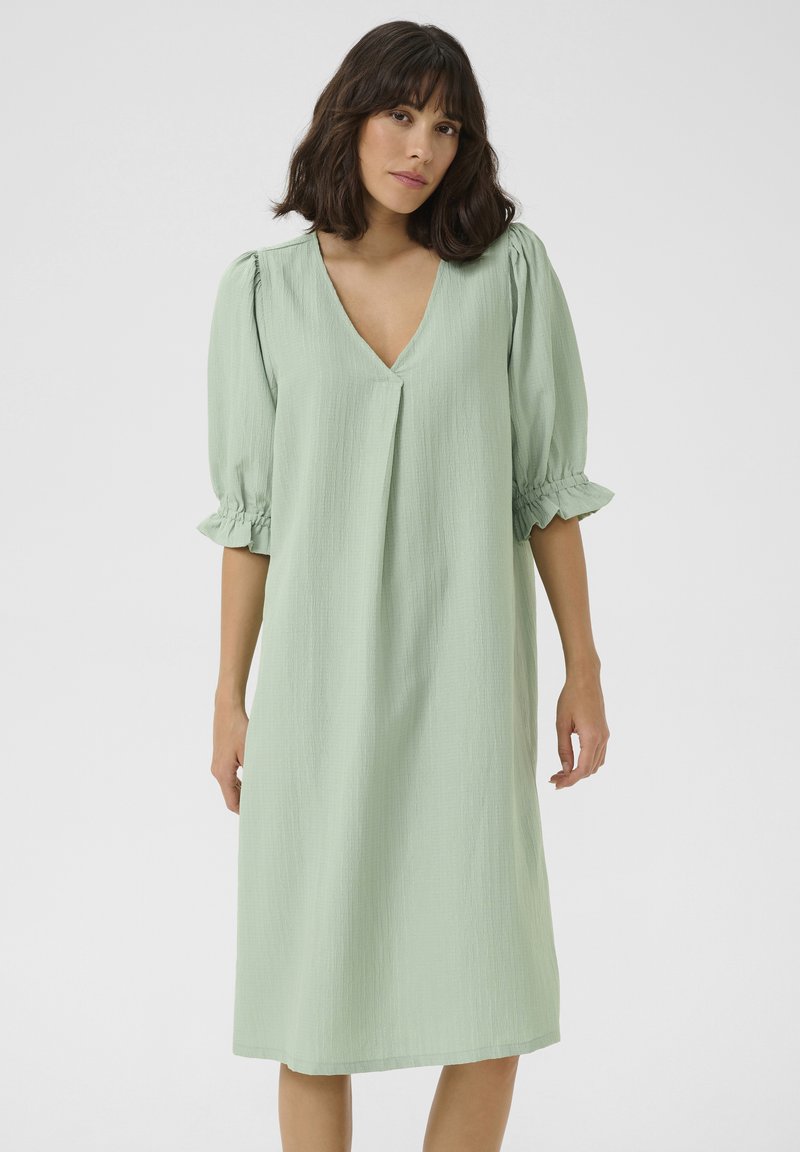 Robe midi vert clair avec un décolleté en V, des manches courtes bouffantes et des poignets froncés. Fabriquée en tissu texturé, elle présente une coupe décontractée et une longueur jusqu'aux genoux.