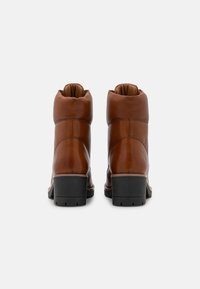 Bottines en cuir marron avec une finition lisse, bout arrondi et un petit talon noir. L'intérieur est doublé d'un rembourrage doux pour un confort accru.