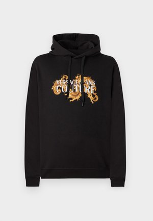 Black hoodie with front drawstrings featuring "Versace Jeans Couture" text in white and gold ornate decorative design.