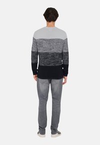 Pulover tricotat pentru bărbați, cu un design în degradé în nuanțe de gri, negru și bleumarin. Textură rib batută la tiv și manșete. Asortat cu blugi gri și adidași.