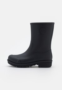 Botte de pluie en caoutchouc mid-calf noire mate avec semelle texturée et logo circulaire embossé sur le côté supérieur, inclinée à gauche sur un fond blanc.