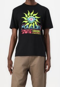 Camiseta de algodón negra con un vibrante estampado gráfico que presenta un diseño de un ojo y un sol en verde, amarillo y rojo. Manga corta, ajuste clásico.