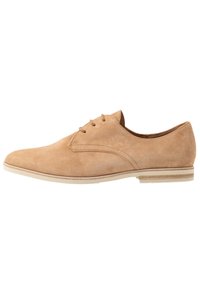 Tan suède veterschoenen met een ronde neus, minimale stiksels en een contrasterende witte rubberen zool. Glad textuur, klassiek ontwerp.