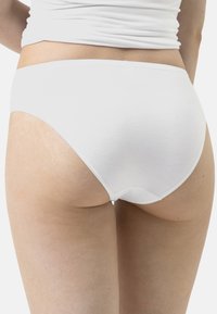 Completi in cotone bianco con un design a vita alta, texture morbida e dettagli di cucitura minimi, che mostrano una finitura liscia e uno stile semplice.