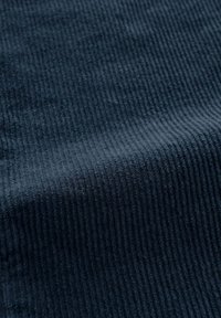 Donker marineblauw ribstof met een zachte, gestructureerde oppervlakte. Het patroon heeft verticale lijnen die diepte en visuele interesse creëren.