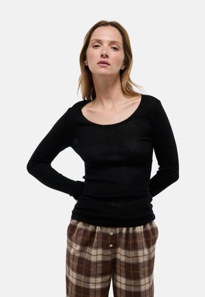 Haut noir à manches longues avec un col rond, texture côtelée et design ajusté, associé à un pantalon à carreaux marron avec deux boutons.