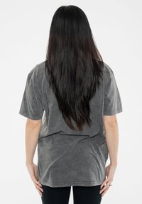Gray oversized t-shirt with short sleeves, made of soft fabric. Features a relaxed fit and minimal seams, worn with black leggings.