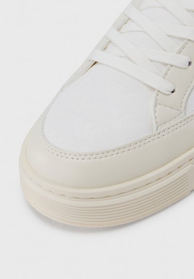Bela superga iz gladkega sintetičnega usnja, zgornji del iz teksturirane platnene tkanine, okrogel sprednji del in ravne vezalke s šivi kot poudarki.