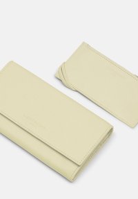 Zestaw żółtych skórzanych portfeli, w skład którego wchodzi długi portfel o gładkiej fakturze oraz osobny holder na karty z twistowym akcentem. Czyste linie, minimalistyczny design.