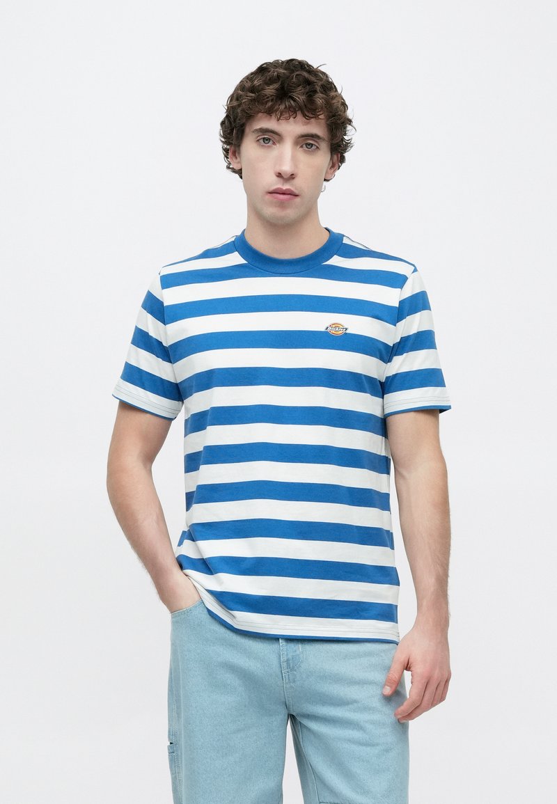 Maglietta a righe blu e bianche in cotone, con scollo rotondo e maniche corte. Piccolo dettaglio logo sul petto. Vestibilità casual.