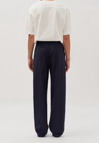 Marina vida byxor med en slät textur, hög midja och två bakfickor; matchade med en enkel vit T-shirt.