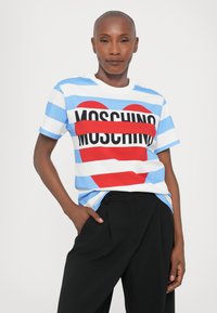 Stripet kortermet T-skjorte i lyseblå og hvit med et rødt hjerte og "MOSCHINO" i fete svarte bokstaver over forsiden.