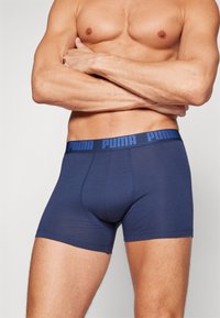 Mörkblå boxerkalsonger i mjukt tyg, med en platt midjeband som har "PUMA"-logotypen i kontrasterande blått. Slät, åtsittande design.