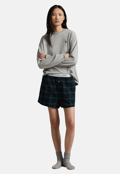 Grå långärmad tröja med en liten logotyp, i kombination med mörkgröna rutiga boxershorts med en elastisk midja med varumärke. Grå strumpor.