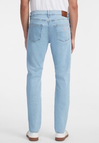 Svetlo modre kavbojke s slim fit krojem, ki imajo pet žepov, usnjeno nalepko na zadnjem pasu in subtilne šive.