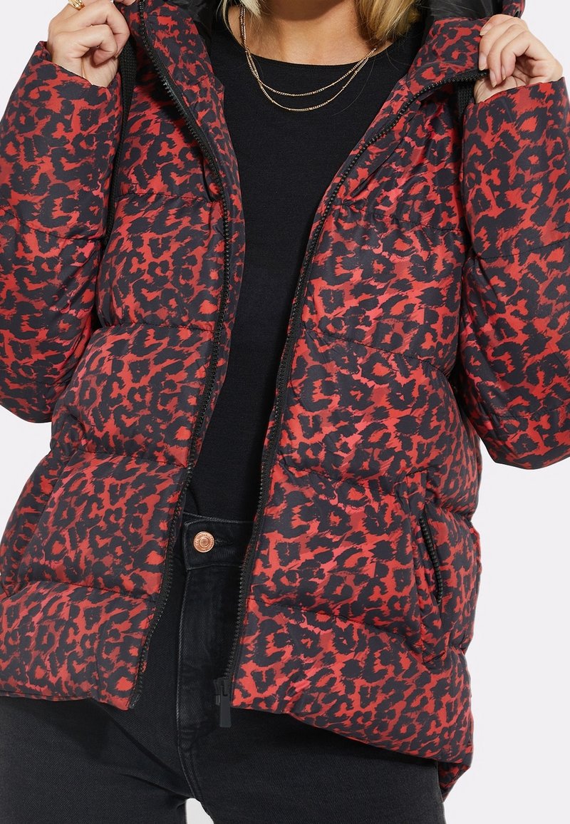 Puffjakke med et iøjnefaldende mønster i rød og sort leopardprint, lynlås og hætte. Fremstillet af et blødt, quiltet stof.