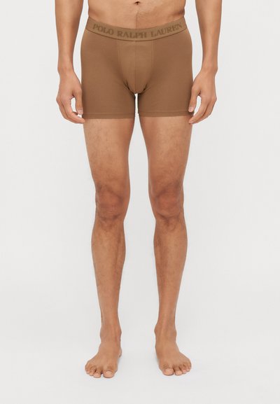 Barna pamut boxer short, logóval díszített derékrésszel. Formázott kivitel, puha tapintás és combközép hosszúság. Nincsenek minták vagy díszítések.
