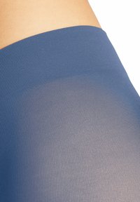 Tessuto blu a costine con una finitura texture, caratterizzato da una transizione fluida a una sezione trasparente, evidenziando qualità morbide e leggere.