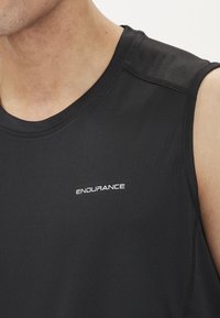 Sort atletisk tanktop med en blød tekstur; har en rund halsudskæring og et hvidt "ENDURANCE" logo på venstre brystområde.