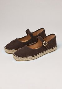 Espadrillas in suede marrone con punta arrotondata, cinturino alla caviglia e suola in juta intrecciata. Materiale testurizzato e dettagli di cucitura leggera a contrasto.