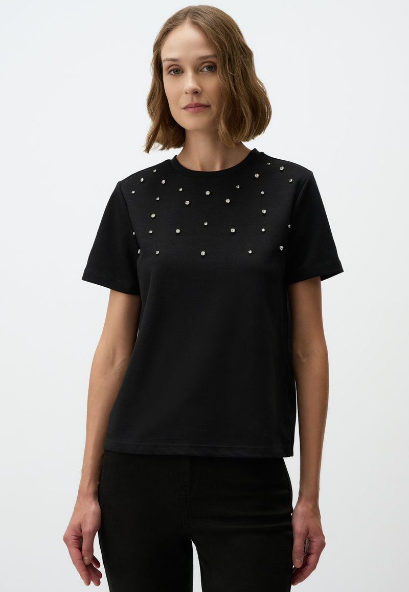 Zwarte T-shirt met korte mouwen, versierd met verspreide zilveren details aan de voorkant, ronde halslijn en een relaxte pasvorm. Glad stofoppervlak.