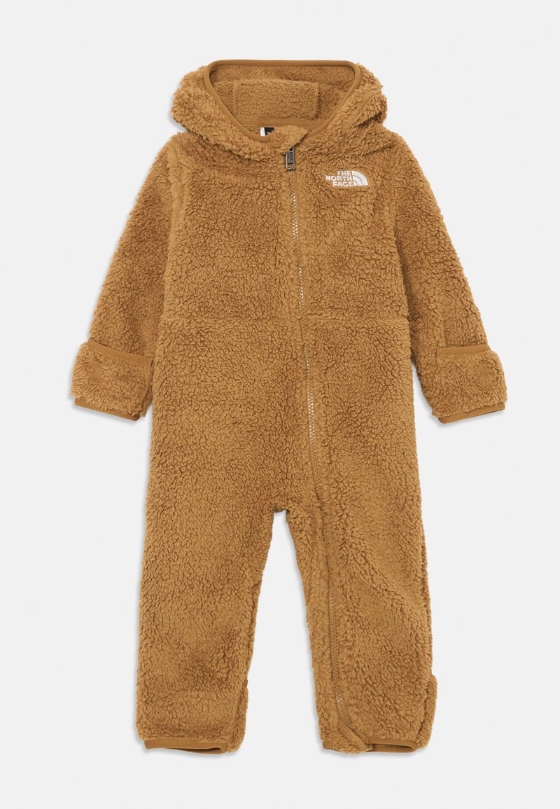 Macacão de fleece castanho com fecho de correr à frente, capuz e punhos elásticos. Apresenta um pequeno logo branco no lado esquerdo do peito. Textura suave.