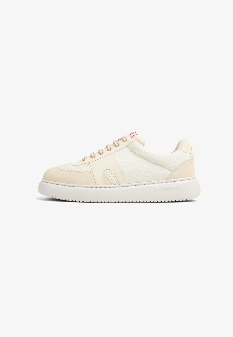 Zapatillas deportivas beige con una combinación de materiales suaves y texturizados. Punta redondeada, suela blanca plana y cordones beige. Detalles sutiles en el costado.