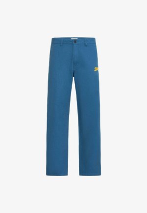 Blå bukser lavet af tekstureret stof. Har lukning med knapper og gul broderet logo på låret. Design med lige ben.