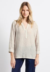 Linned skjorta med randigt mönster i beige och ljusbrun, med V-ringning, långa ärmar och uppvikta ärmslut. Har en avslappnad passform och en naturlig textur.