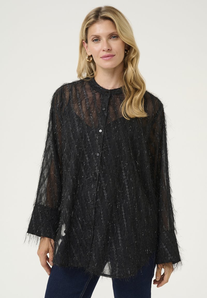 Melnā caurspīdīgā blūze ar teksturētu, pūkainu materiālu. Aprīkota ar pogu priekšpusi, garām piedurknēm un smalku spīdīgu rakstu visā virsma.