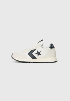 Hvide sneakers med sort stjerne og trekantet design. Har suedelæder detaljer, sort sål og en trækflig ved hælen. Klassisk retro stil.