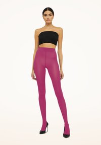 Leggings magenta con una texture liscia e elastica, vita alta e finitura trasparente, abbinati a un crop top nero e tacchi alti.