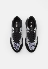 Baskets avec une tige textile à motif noir et blanc, accents argentés, lacets noirs et détails de logo sur la languette. Design à profil bas.