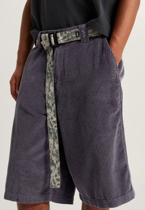 Bordeaux shorts i fløjlsfiber med en tekstureret overflade og et grønt camouflage-bælte. Har sidelommer og en løs pasform.