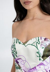 Abito senza spalline con scollatura a V, caratterizzato da motivi astratti verdi e viola su un tessuto satinato bianco, con una texture morbida.