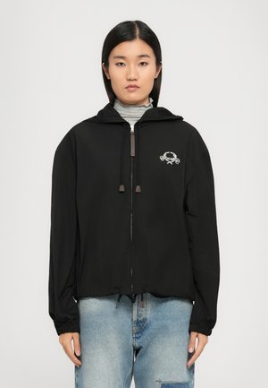 Schwarze Zip-Jacke mit Kapuze, ausgestattet mit elastischen Bündchen, einem Kordelzug am Saum und einem weißen gestickten Logo auf der linken Brust.