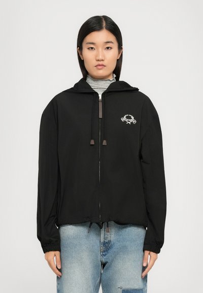 Veste noire à fermeture éclair avec capuche, dotée de poignets élastiqués, d'un ourlet à cordon de serrage et d'un logo brodé blanc sur la poitrine gauche.