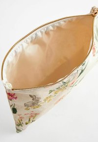 Beżowy woreczek z tkaniny z złotym zamkiem, ozdobiony kwiatowymi wzorami oraz wzorem króliczków, pokazany otwarty z pustym, jasnobeżowym wnętrzem.